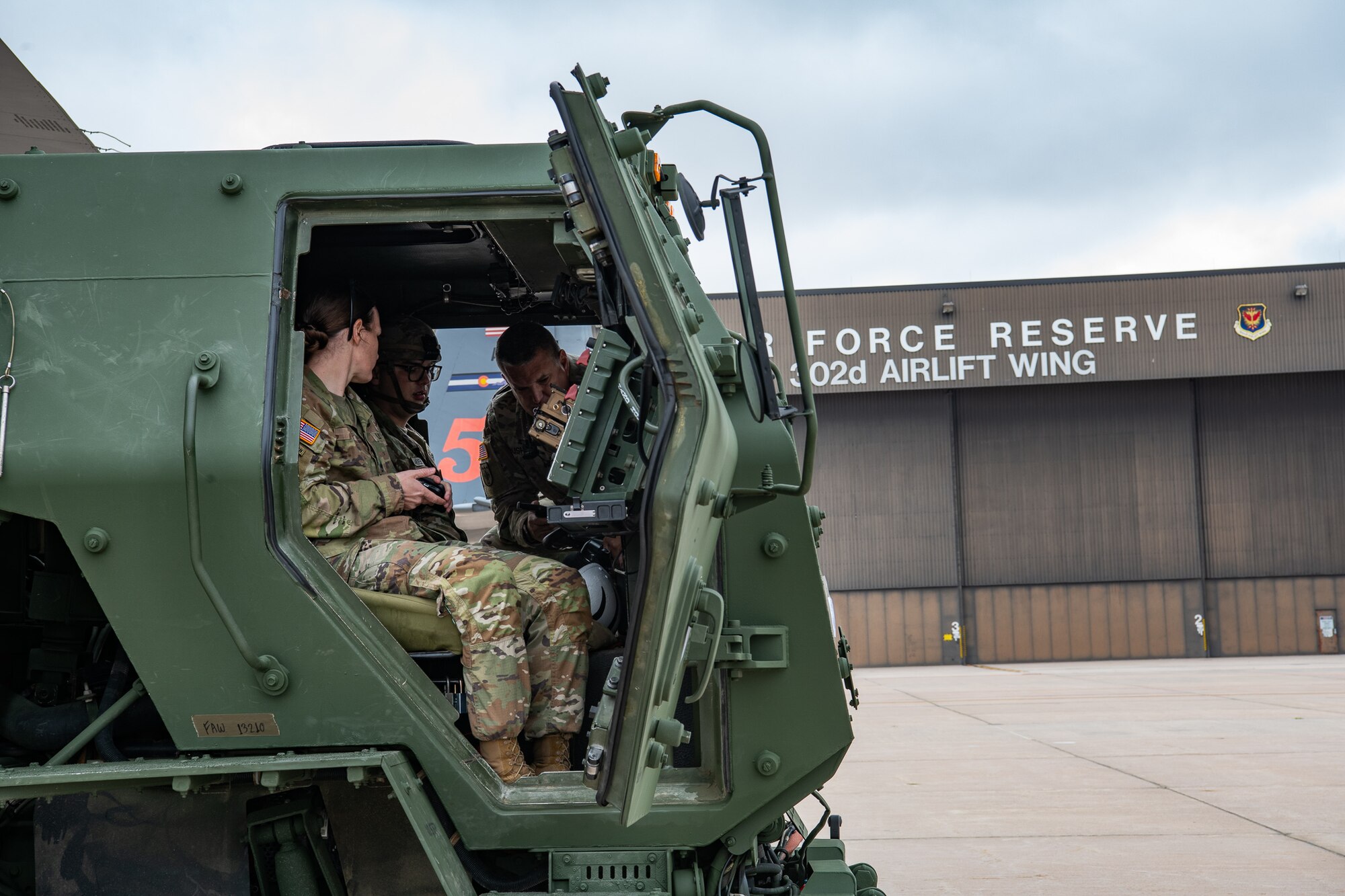 Three servicemembers in the personnel compartment of a tactical truck.