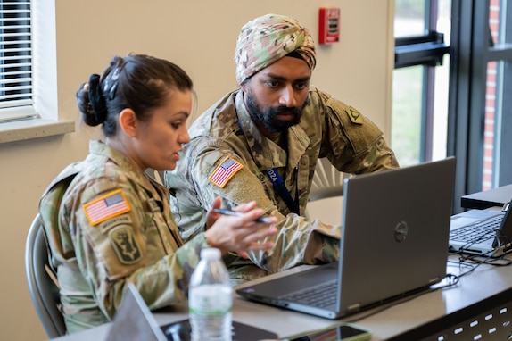 Service members type on computers.