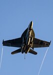 F/A 18 aircraft seen from below climbs into a blue sky.