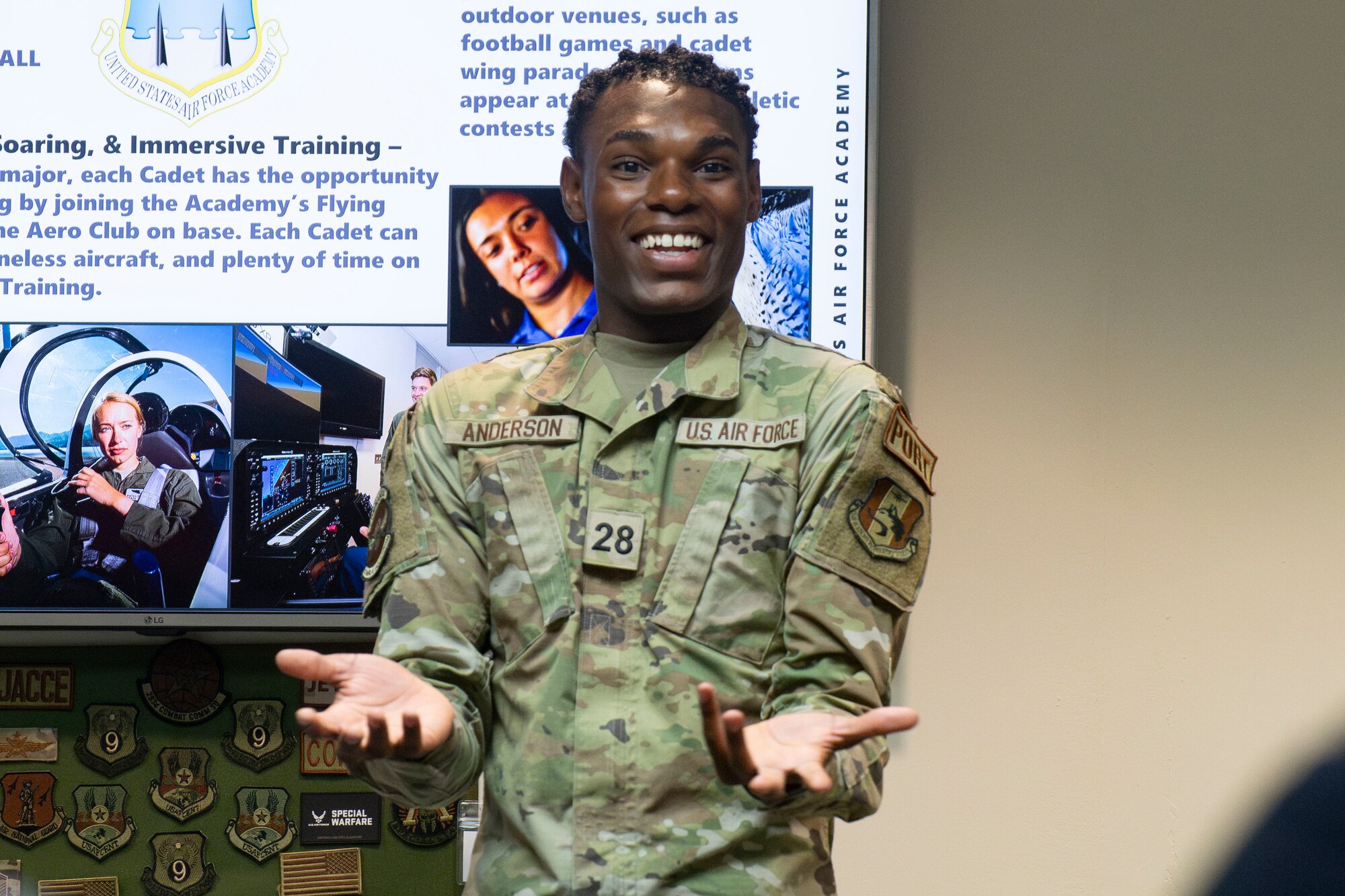 A man smiles while speaking to a classroom of people.