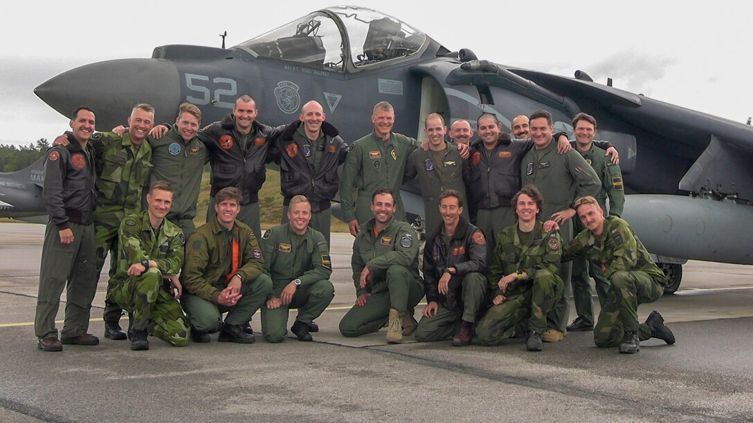 A U.S. Marine Corps pilots with Marine Medium Tiltrotor Squadron (VMM) 365 (Reinforced), 24th Marine Expeditionary Unit (MEU) Special Operations Capable (SOC) and Swedish Air Force pilots with 172 Fighter Squadron, pose for a group photo in front of an AV-8B Harrier assigned to VMM-365 (REIN), 24th MEU (SOC), at Ronneby Airport, Sweden, during Baltic Operations (BALTOPS) 24, June 10, 2024. BALTOPS 24 is the premier maritime-focused exercise in the Baltic region. The exercise, led by U.S. Naval forces Europe-Africa and executed by Naval Striking and Support Forces NATO, provides a unique training opportunity to strengthen combined response capabilities critical to preserving freedom of navigation and security in the Baltic Sea. (U.S. Marine Corps photo by Cpl. Elton Taylor)