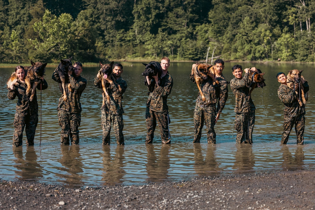 U.S. Marines with Provost Marshall Office K-9, pose for a group photo after conducting water aggression training with military working dogs on Marine Corps Base Quantico, Virginia, June 14, 2024. MWDs receive follow on training upon arriving at their assigned units; one of those trainings is water aggression which develops their comfortability in water-based environments. (U.S. Marine Corps photo by Lance Cpl. Joaquin Dela Torre)