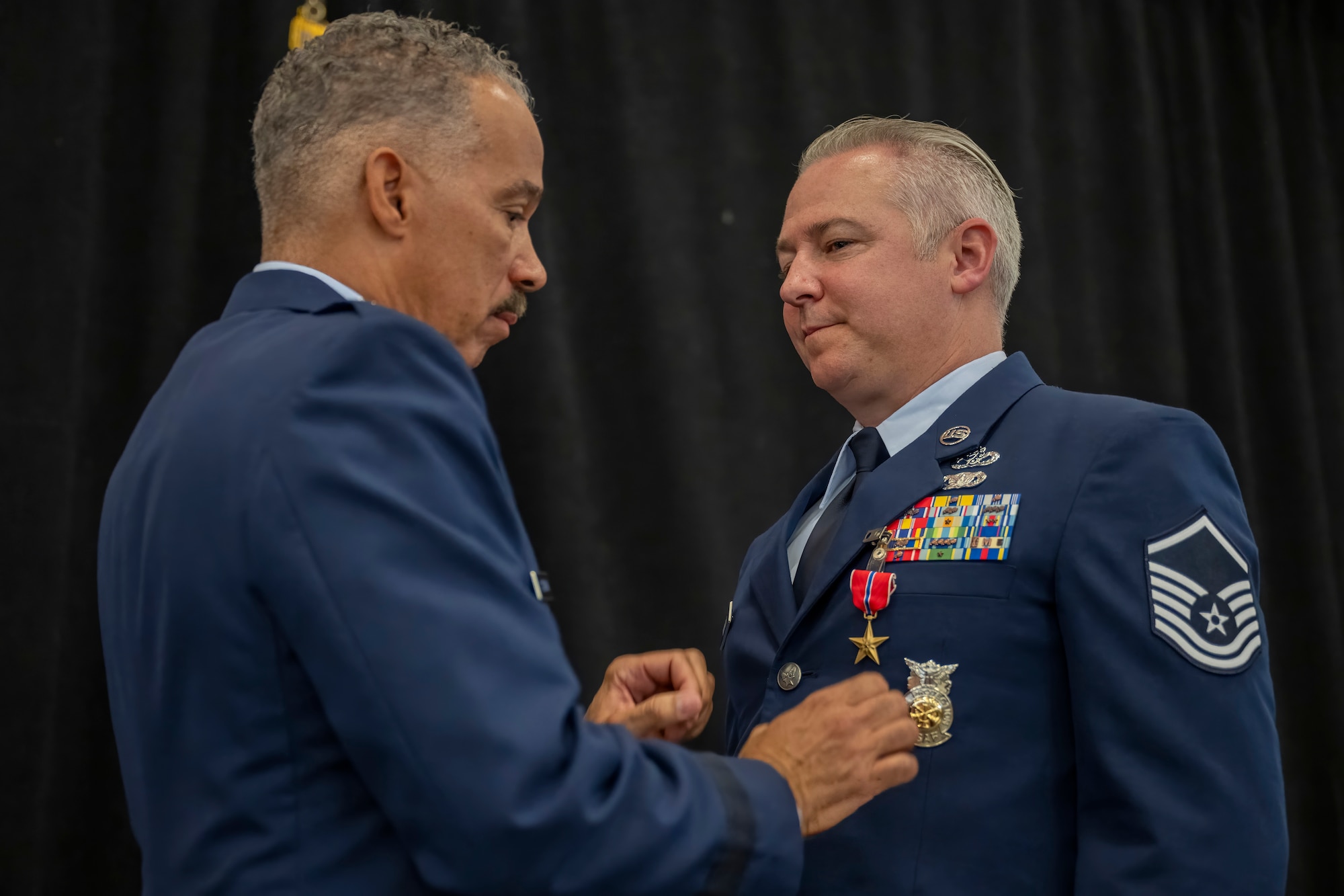 Brig. Gen. David Cochran, Commander of the West Virginia Air National Guard, pins the Bronze Star on Master Sgt. Andrew Mencin, a firefighter assigned to the 130th Airlift Wing during a ceremony held June 8, 2024, at McLaughlin Air National Guard Base, Charleston, W.Va. Mencin earned the Bronze Star for actions during a six-month deployment in support of Operation Inherent Resolve. (U.S. Air National Guard photo by 2nd Lt. De-Juan Haley)