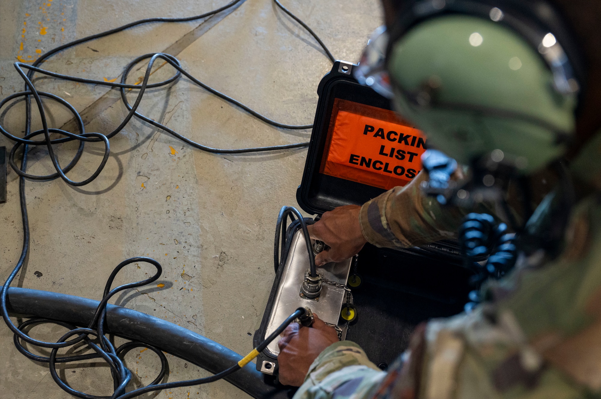 U.S. Air Force Airman 1st Class Nicolas Rodriguez, 49th Component Maintenance Squadron electrical environmental systems apprentice, sets up a communications W cord at Holloman Air Force Base, New Mexico, May 20, 2024. The device accelerates the training process by allowing more personnel to engage in real-time communication, ensuring that maintenance tasks are completed more efficiently and safely. (U.S. Air Force photo by Senior Airman Isaiah Pedrazzini)