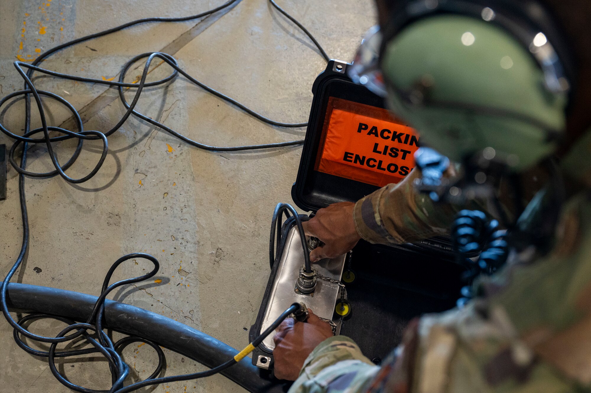 U.S. Air Force Airman 1st Class Nicolas Rodriguez, 49th Component Maintenance Squadron electrical environmental systems apprentice, sets up a communications W cord at Holloman Air Force Base, New Mexico, May 20, 2024. The device accelerates the training process by allowing more personnel to engage in real-time communication, ensuring that maintenance tasks are completed more efficiently and safely. (U.S. Air Force photo by Senior Airman Isaiah Pedrazzini)