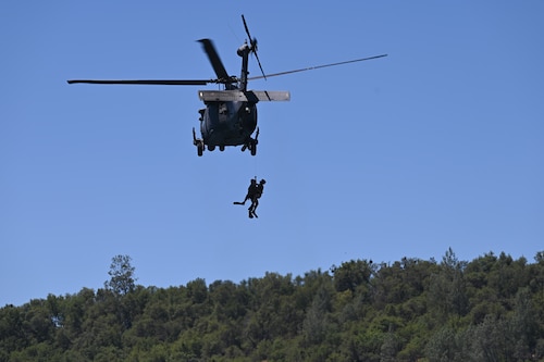 A Sikorsky HH-60G Pave Hawk lowers a pair of U.S. Air Force pararescue jumpers from the 129th Rescue Wing into Englebright Lake, Smartsville, California on June 6, 2024.