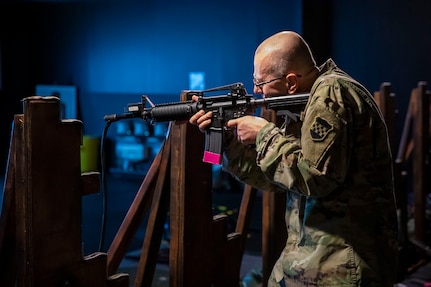 A soldier aims a weapon in a training facility.