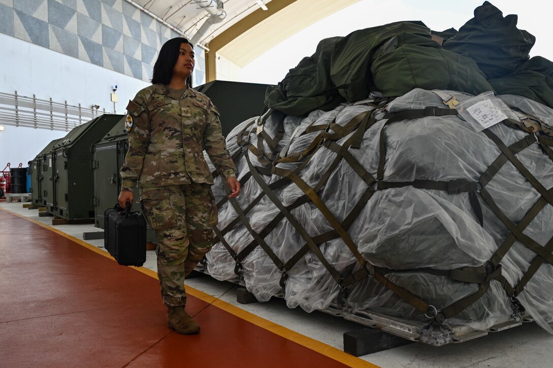 U.S. Air Force Staff Sgt. Priscilla Ramirez, 37th Expeditionary Bomb Squadron all-source intelligence analyst non-commissioned officer in-charge, walks equipment into a Hangar where the 37th EBS is operating out of at Andersen Air Force Base, Guam, June 17, 2024. The U.S. Air Force routinely deploys a variety of aircraft and units throughout the Indo-Pacific area of operations in support of geographic combatant command objectives and training. (U.S. Air Force photo by Staff Sgt. Jake Jacobsen)