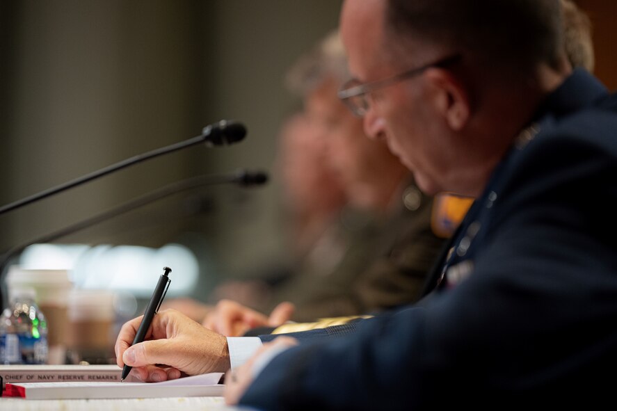 Military service members sitting at table for congressional hearing.