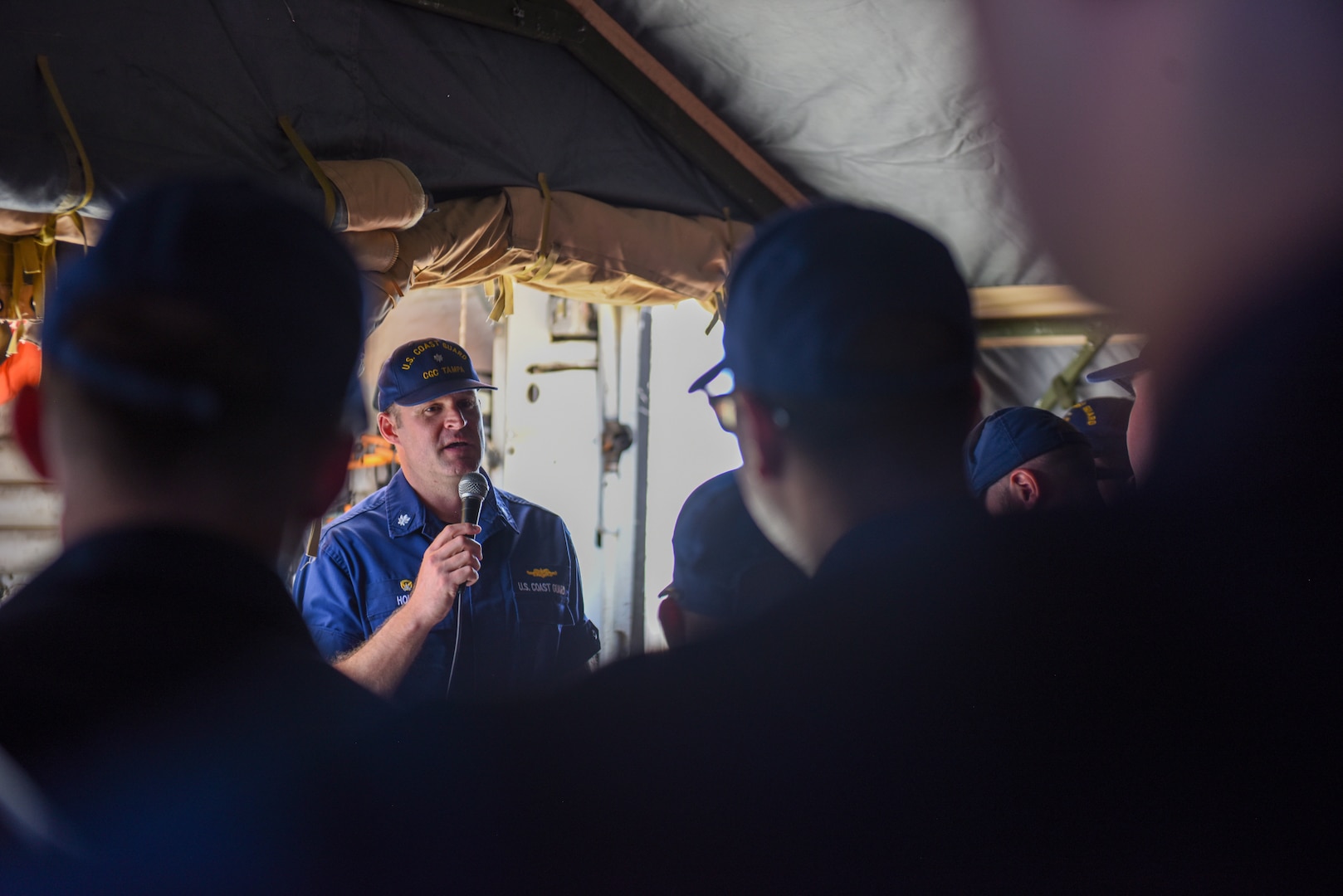 Coast Guard member speaks into a microphone to members of the crew.