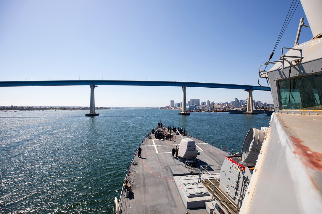 A ship travels in water toward a bridge.