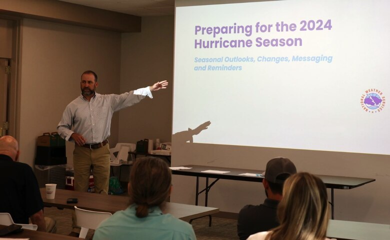 Man stand in front of a classroom giving a presentation on hurricanes.