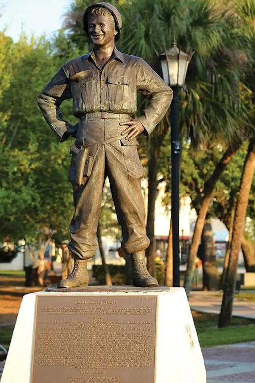 A statue in a park shows a smiling service member standing with their hands on their hips.