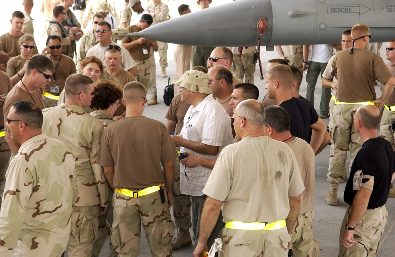 A group of service members gathers around a man.