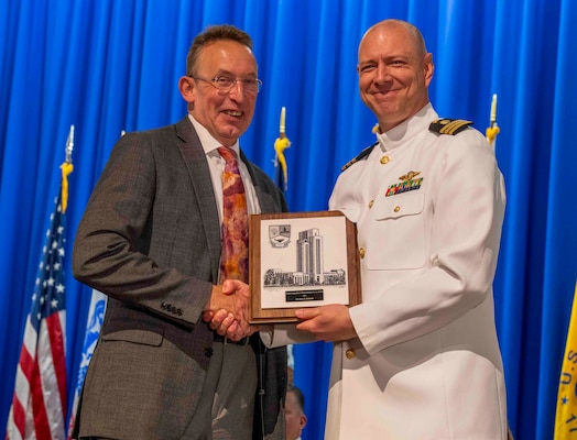 240607-N-JC800-1094 BETHESDA, Md. (Jun. 7, 2024) – Cmdr. Cameron Beck, associate dean for the Naval Postgraduate Dental School (NPDS) at Naval Medical Leader and Professional Development Command, presents Dr. John Schmidt with the Civism Award during the graduation ceremony for the NPDS. (U.S. Navy photo by Mass Communication Specialist 1st Class Heath Zeigler/Released)