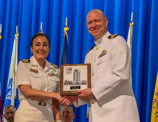 240607-N-JC800-1104 BETHESDA, Md. (Jun. 7, 2024) – Cmdr. Cameron Beck, associate dean for the Naval Postgraduate Dental School (NPDS) at Naval Medical Leader and Professional Development Command, presents Cmdr. Laleh Abdolazadeh with the Dean's Award for Teach Excellence during the graduation ceremony for the NPDS. (U.S. Navy photo by Mass Communication Specialist 1st Class Heath Zeigler/Released)