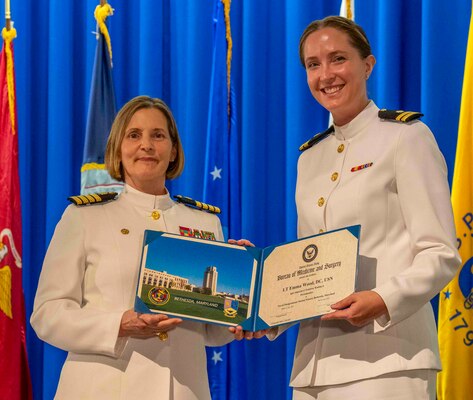 240607-N-JC800-1162 BETHESDA, Md. (Jun. 7, 2024) – Capt. Katharne Shobe, commanding officer of Naval Medical Leader and Professional Development Command, presents Lt. Emma Wood wth her certificate of completion of his residency training in Periodontics during the graduation ceremony for the Naval Postgraduate Dental School. (U.S. Navy photo by Mass Communication Specialist 1st Class Heath Zeigler/Released)