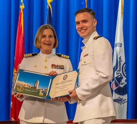 240607-N-JC800-1168 BETHESDA, Md. (Jun. 7, 2024) – Capt. Katharne Shobe, commanding officer of Naval Medical Leader and Professional Development Command, presents Lt. Timothy Daudulin with his certificate of completion of his residency training in Prosthodontics during the graduation ceremony for the Naval Postgraduate Dental School. (U.S. Navy photo by Mass Communication Specialist 1st Class Heath Zeigler/Released)