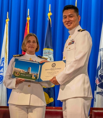 240607-N-JC800-1170 BETHESDA, Md. (Jun. 7, 2024) – Capt. Katharne Shobe, commanding officer of Naval Medical Leader and Professional Development Command, presents Lt. Won Yu with his certificate of completion of his residency training in Prosthodontics during the graduation ceremony for the Naval Postgraduate Dental School. (U.S. Navy photo by Mass Communication Specialist 1st Class Heath Zeigler/Released)