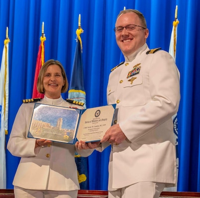 240607-N-JC800-1174 BETHESDA, Md. (Jun. 7, 2024) – Capt. Katharne Shobe, commanding officer of Naval Medical Leader and Professional Development Command, presents Cmdr. Taylor Landon with his certificate of completion of his residency training in Comprehensive Dentistry during the graduation ceremony for the Naval Postgraduate Dental School. (U.S. Navy photo by Mass Communication Specialist 1st Class Heath Zeigler/Released)