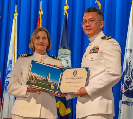 240607-N-JC800-1190 BETHESDA, Md. (Jun. 7, 2024) – Capt. Katharne Shobe, commanding officer of Naval Medical Leader and Professional Development Command, presents Cmdr. Kenny Train with his certificate of completion of his residency training in Comprehensive Dentistry during the graduation ceremony for the Naval Postgraduate Dental School. (U.S. Navy photo by Mass Communication Specialist 1st Class Heath Zeigler/Released)