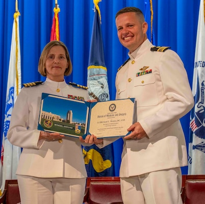 240607-N-JC800-1152 BETHESDA, Md. (Jun. 7, 2024) – Capt. Katharne Shobe, commanding officer of Naval Medical Leader and Professional Development Command, presents Lt. Cmdr. Scott Westra with his certificate of completion of his residency training in Comprehensive Dentistry during the graduation ceremony for the Naval Postgraduate Dental School. (U.S. Navy photo by Mass Communication Specialist 1st Class Heath Zeigler/Released)