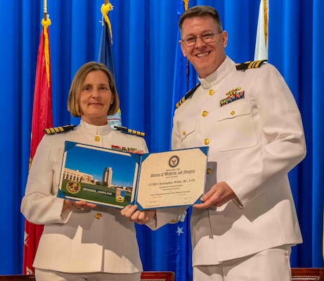 240607-N-JC800-1201 BETHESDA, Md. (Jun. 7, 2024) – Capt. Katharne Shobe, commanding officer of Naval Medical Leader and Professional Development Command, presents Lt. Cmdr. Christopher Wilde with his certificate of completion of his residency training in Comprehensive Dentistry during the graduation ceremony for the Naval Postgraduate Dental School. (U.S. Navy photo by Mass Communication Specialist 1st Class Heath Zeigler/Released)