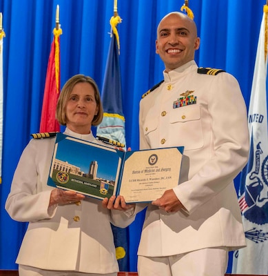 240607-N-JC800-1213 BETHESDA, Md. (Jun. 7, 2024) – Capt. Katharne Shobe, commanding officer of Naval Medical Leader and Professional Development Command, presents Lt. Cmdr. Ricardo Wassmer with his certificate of completion of his residency training in Endodontics during the graduation ceremony for the Naval Postgraduate Dental School. (U.S. Navy photo by Mass Communication Specialist 1st Class Heath Zeigler/Released)