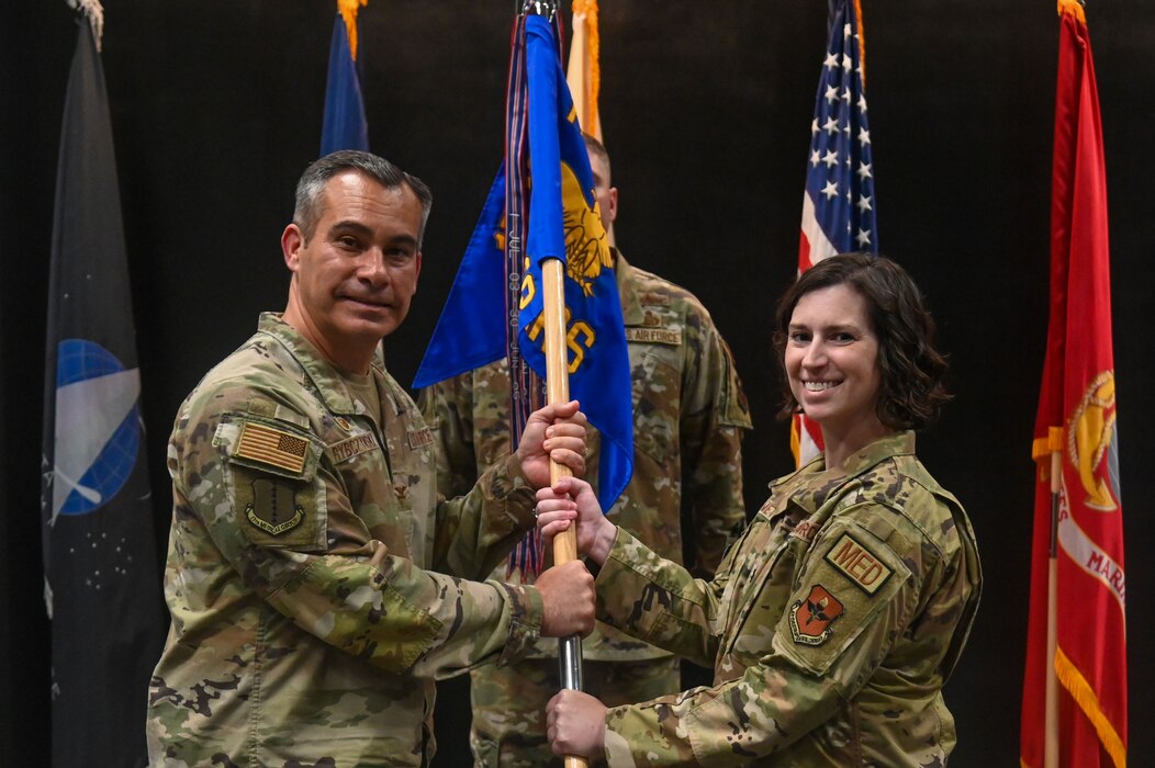 U.S. Air Force Col. Ian Rybczynski, 17th Medical Group commander, hands over the guidon to Lt. Col. Shelley Metcalf, 17th Operational Medical Readiness Squadron incoming commander, at the Powell Event Center, Goodfellow Air Force Base, Texas, June 17, 2024. The change of command ceremony is a military tradition, which illustrates the formal transfer of authority by the passing of the guidon from the departing commander to the incoming commander.  (U.S. Air Force photo by Airman 1st Class James Salellas)