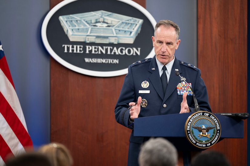 A man in a military uniform stands behind a lectern.