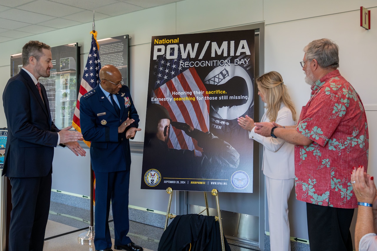 Four people look at a poster displayed on an easel.