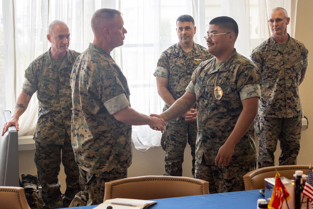 U.S. Marine Corps Lance Cpl. Omar Maldonado, a military police officer with the Marine Corps Air Station Iwakuni Provost Marshal Office and New Jersey native, shakes hands with Maj. Gen. David Maxwell, the commanding general of Marine Corps Installations Command, and an Oregon native, after being recognized for his  work in the Pass and Registration Section of PMO, MCAS Iwakuni, Japan, June 10, 2024. Leadership from MCICOM toured MCAS Iwakuni to speak with service members and learn more about the day-to-day work on the air station. (U.S. Marine Corps photo by Sgt. Lance Kell)