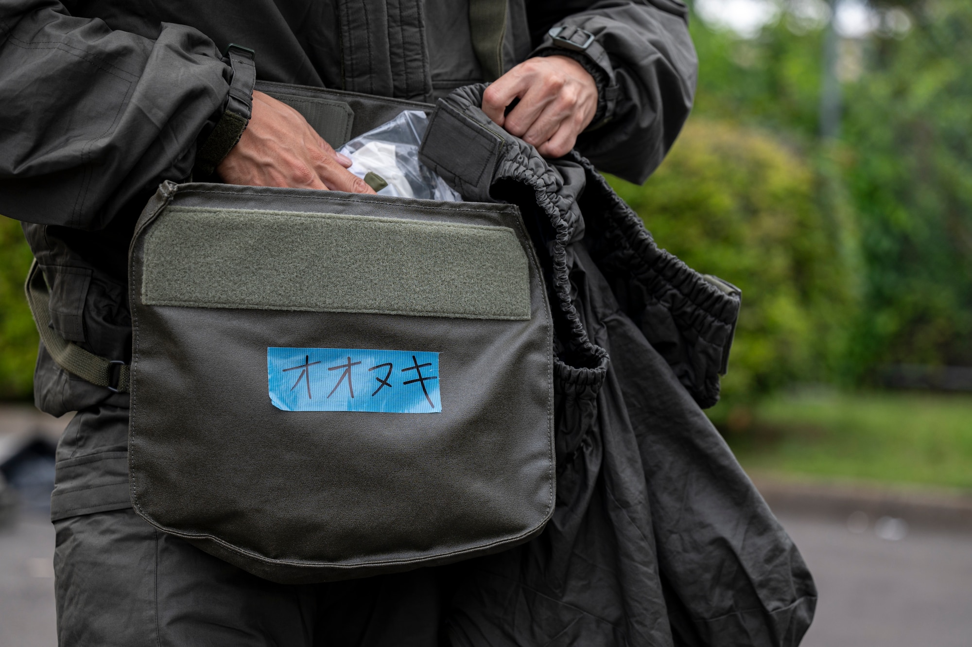 A member assigned to the Japan Air Self-Defense Force Operations Support Wing reaches into a gas mask carrier bag.