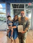 Top 13 recruiter poses with wife and child during an award ceremony