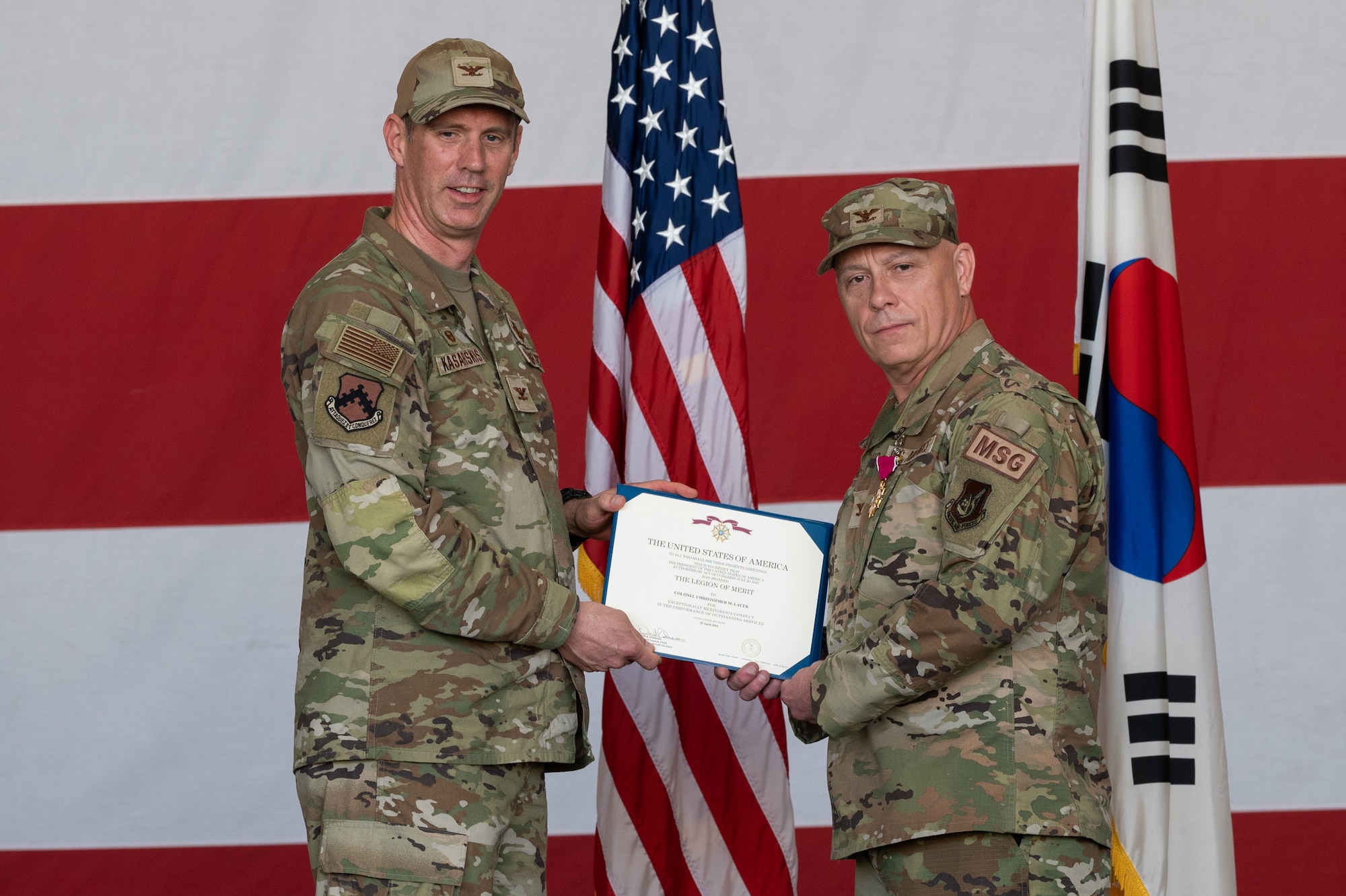 U.S. Air Force Col. Peter Kasarskis, left, 8th Fighter Wing commander, presents Col. Christopher Lacek, 
8th Mission Support Group outgoing commander, with the Legion of Merit during the 8th MSG change of command ceremony at Kunsan Air Base.
