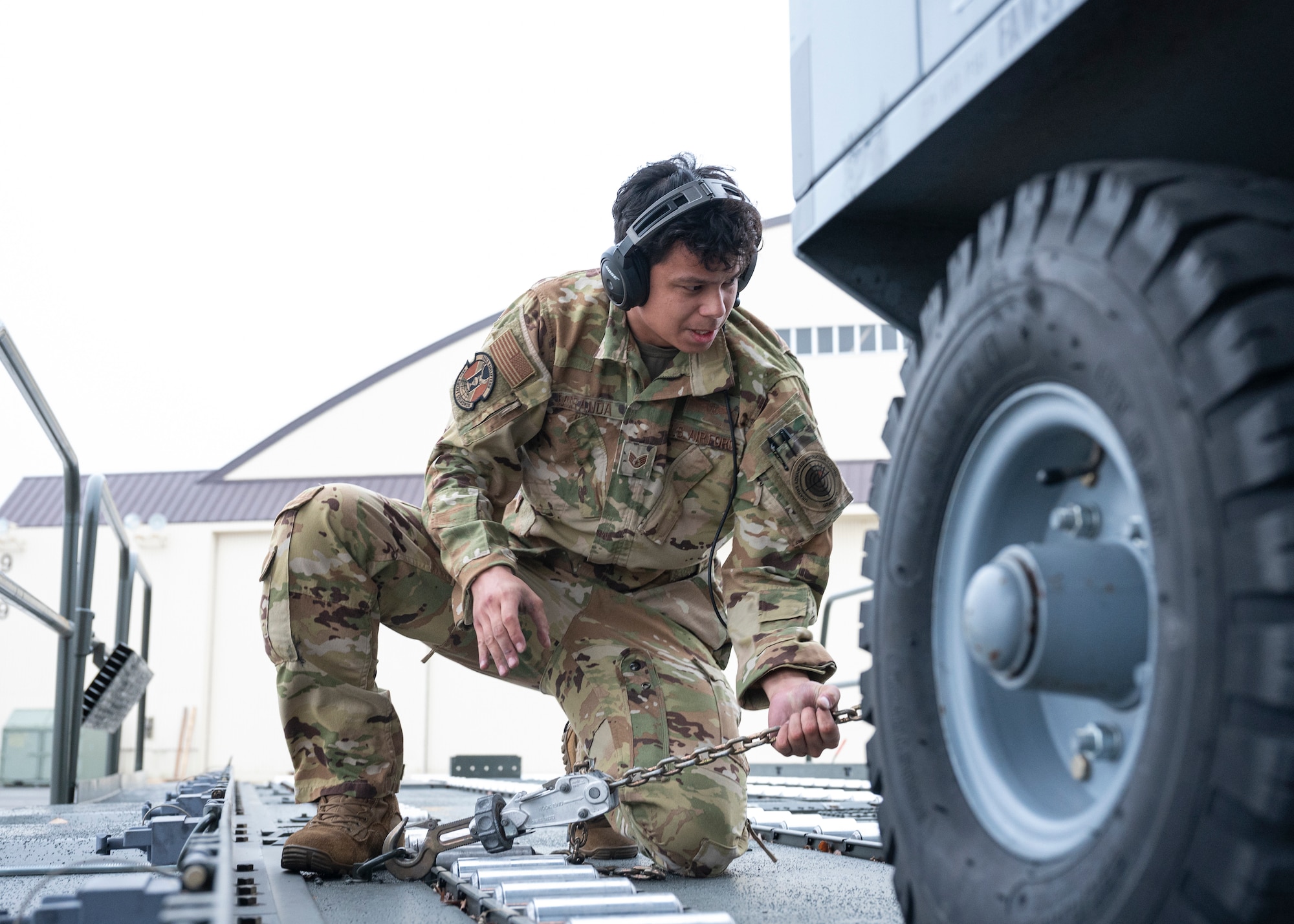 An airman loosens a chain from a hydraulic test stand.