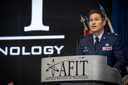 Lt Col Talafuse gives a speech standing behind a podium with AFIT logo