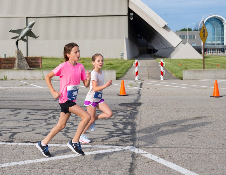 Two preteen girls run past the Air Force Museum.