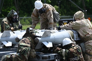 Airmen in chemical, biological, radiological or nuclear gear inspect munitions.