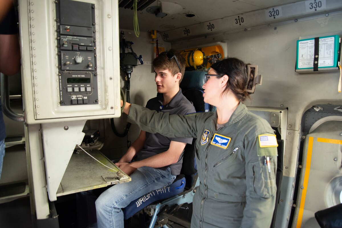 Female Airmen in flight suite talks with a student inside the C-17 Globemaster III.