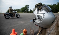 U.S. Army Sgt. 1st Class Vanesa Breckenridge rides a motorcycle past a helmet during the Motorcycle Safety Foundation course on June 17, 2024, at Fort Knox, Kentucky. The course aims to improve rider safety and skills among military personnel. (U.S. Army photo by Sgt. Tyler Brock)