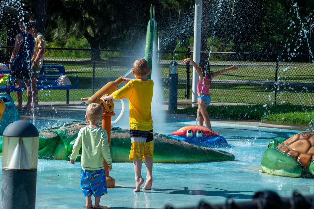 Military children play on the splash pad during a Hearts Apart dinner at Moody Air Force Base, Georgia, June 20, 2024. This quarter’s Hearts Apart dinner offered free food and an escape from the South Georgia heat. (U.S. Air Force photo by Airman 1st Class Iain Stanley)