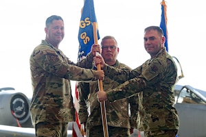 U.S. Air Force Maj. Bryan Saam, right, assumes command of the 75th Fighter Generation Squadron as Col. Bobby Buckner, 23rd Maintenance Group commander, left, passes him a guidon for a change of command ceremony at Moody Air Force Base, Georgia, June 21, 2024. The passing of the flag is a military tradition signifying the change of authority and responsibility of a unit from one commander to another.  (U.S. Air Force photo by Airman 1st Class Iain Stanley)
