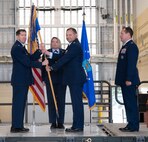 U.S. Air Force Col. Christopher Cain, outgoing 5th Operations Group (5th OG) commander (center), hands the guidon to Col. Daniel Hoadley, 5th Bomb Wing commander (left), during the 5th OG change of command ceremony at Minot Air Force Base, North Dakota, June 21, 2024. Cain gave the guidon to Hoadley during the ceremony, symbolically handing off command of the 5th OG. (U.S. Air Force photo by Airman 1st Class Luis Gomez)