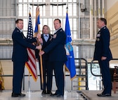 U.S. Air Force Col. John Burrell, incoming 5th Operations Group (5th OG) commander (center), accepts the guidon from Col. Daniel Hoadley, 5th Bomb Wing commander (left), during the 5th OG change of command ceremony at Minot Air Force Base, North Dakota, June 21, 2024. Hoadley passed the guidon to Burrell during the ceremony, symbolically giving him command of the 5th OG. (U.S. Air Force photo by Airman 1st Class Luis Gomez)