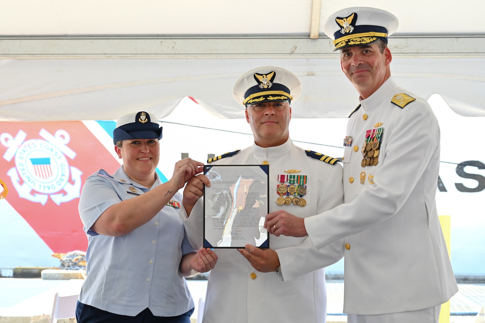 Vice Adm. Nathan Moore, Atlantic Area commander, right, poses for a photo with Cmdr. Aaron Kowalczk, commanding officer of U.S. Coast Guard Cutter Dauntless (WMEC 624), and Chief Petty Officer Stephanie Castillo, command silver badge aboard Dauntless, after the cutter was awarded the Coast Guard Unit Commendation, the highest peacetime award that can be given to military commands in the U.S. Coast Guard, June 21, 2024, in Pensacola, Florida. Dauntless was recognized during a heritage recognition ceremony after 56 years of service to the nation in the presence of current and former crew members, family, and friends before it was placed in commission, special status. (U.S. Coast Guard photo by Petty Officer 2nd Class Brandon Hillard)