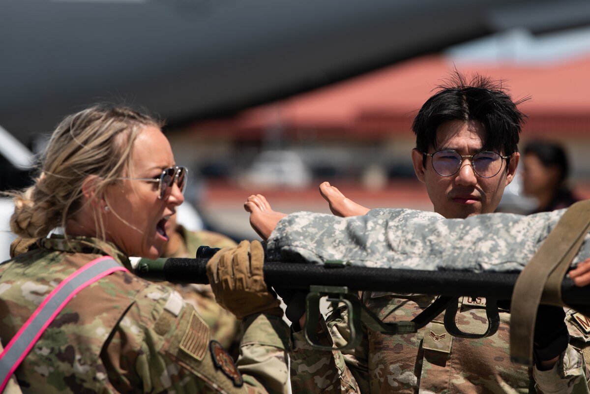 Airmen lift a simulated patient onto an ambulance bus