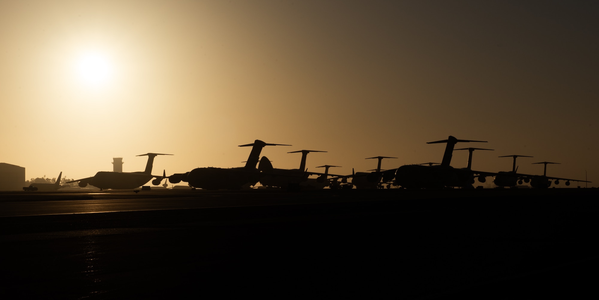 C-17s parked on flight line with sun rising behind them
