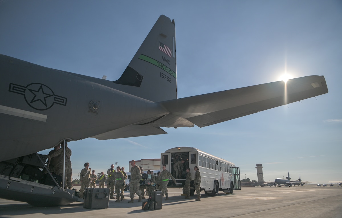 Airmen transport simulated patients from an ambulance bus onto an aircraft