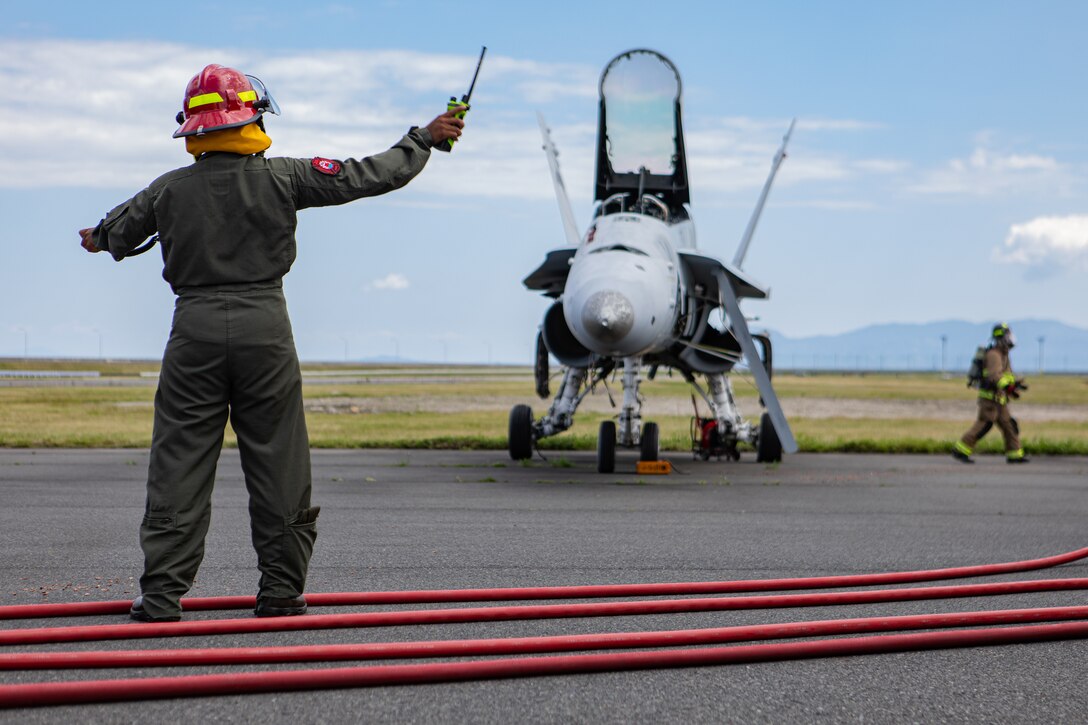 U.S. Marine Corps Sgt. Yasmine Huley-Morris, the station captain of Aircraft Rescue and Firefighting, Headquarters and Headquarters Squadron, Marine Corps Air Station Iwakuni, and a native of Virginia, uses hand and arm signals to direct Marines during a simulated ARFF F-18 hot breaks, spontaneous combustion training exercise at MCAS Iwakuni, Japan, June 4, 2024. Huley-Morris recently received the Military Firefighter of the Year award for all military services. The award recognizes the firefighter's accomplishments of the preceding year for setting the example of professional activities and career development goals.